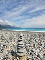 A stack of rocks on a beach with a blue sky photo