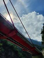 A red bridge with a rainbow in the sky photo