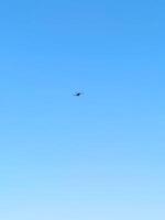 A drone hovers against a backdrop of clear blue sky, likely surveying the area or capturing images for mapping or monitoring purposes photo