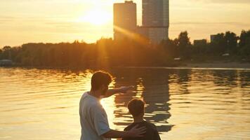 Father and son enjoy the view of the city, with the setting sun creating a picturesque backdrop over the water. video