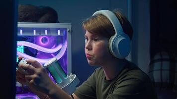 Young man is fully engaged in gaming on a computer, using a gaming controller, headphones, and a microphone to communicate with his teammates. video