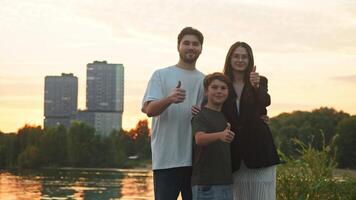 Portrait of a family of three, consisting of a father, mother, and child. They are all looking directly at the camera, smiling warmly and giving a thumbs up. video