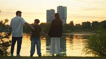 Parents are playing a game with their child in the public park. They are pulling each other closer to demonstrate their affection for one another. video