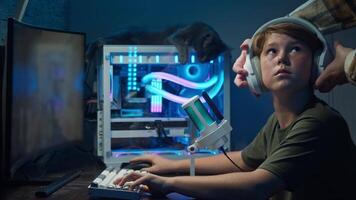 The older brother removes the younger one from the computer and sits down himself to play an online shooter with pleasure. Slow motion video