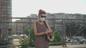 Caucasian mature woman wearing mask is walking in city with small dog in carrying bag and using hand sanitizer, during coronavirus epidemic. An elderly dog owner uses an antiseptic. Covid time video