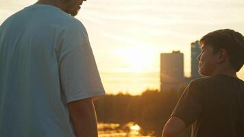 The older sibling embraces the younger sibling against the backdrop of a picturesque sunset in a metropolitan setting. video