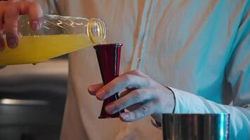 Bartender pours concentrated egg yolk from a jigger bottle in order to add its exotic cocktail. Close up. Slow motion video