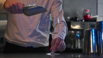 A bartender in a nightclub is seen pouring ice cubes into a glass, in excess, while standing behind the bar. video