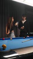 datum mellan två älskande i en bar med biljard. de dryck cocktails och ha en trevlig konversation i mellan de spel. vertikal video