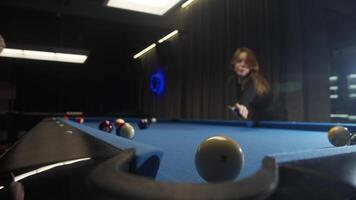 A beautiful young red-haired woman drives a red American pool ball into the pocket of a blue billiard table with a precise blow video