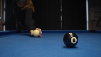 Close-up shot of powerful and precise strike by young woman with red-haired hair, on black pool ball numbered 8, at conclusion of game. video