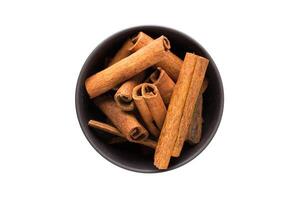 cinnamon sticks in clay bowl isolated on white background. Seasoning or spice top view photo