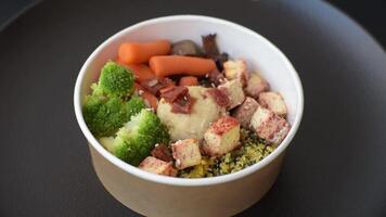 Colorful vegan vegetarian dish consists of tofu, broccoli, quinoa, mushrooms and carrots on a dark textured background video