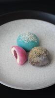 Delicious colorful asian mochi sweets with rice dough shell and fruit filling on dark concrete background video
