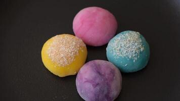Delicious colorful asian mochi sweets with rice dough shell and fruit filling on dark concrete background video