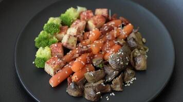 Colorful vegan vegetarian dish consists of tofu, broccoli, quinoa, mushrooms and carrots on a dark textured background video