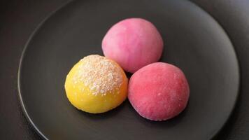 Delicious colorful asian mochi sweets with rice dough shell and fruit filling on dark concrete background video