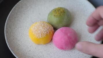 Delicious colorful asian mochi sweets with rice dough shell and fruit filling on dark concrete background video