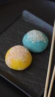 Delicious colorful asian mochi sweets with rice dough shell and fruit filling on dark concrete background video