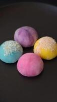 Delicious colorful asian mochi sweets with rice dough shell and fruit filling on dark concrete background video