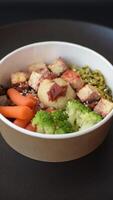 Colorful vegan vegetarian dish consists of tofu, broccoli, quinoa, mushrooms and carrots on a dark textured background video