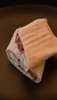 Roll with pita, meat, tomatoes, cheese, sauce, salt and spices on a dark texture background video