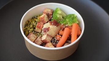 Colorful vegan vegetarian dish consists of tofu, broccoli, quinoa, mushrooms and carrots on a dark textured background video
