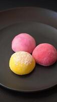 Delicious colorful asian mochi sweets with rice dough shell and fruit filling on dark concrete background video
