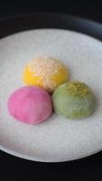Delicious colorful asian mochi sweets with rice dough shell and fruit filling on dark concrete background video