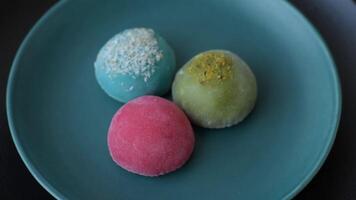 Delicious colorful asian mochi sweets with rice dough shell and fruit filling on dark concrete background video