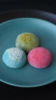 Delicious colorful asian mochi sweets with rice dough shell and fruit filling on dark concrete background video