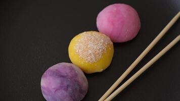 Delicious colorful asian mochi sweets with rice dough shell and fruit filling on dark concrete background video