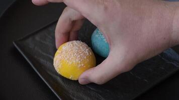 Delicious colorful asian mochi sweets with rice dough shell and fruit filling on dark concrete background video
