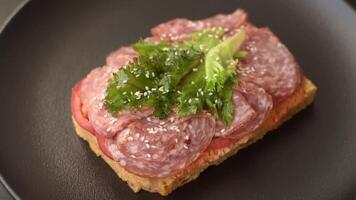 Focaccia with salami, cheese, tomatoes, arugula, spices and herbs on a dark concrete background video