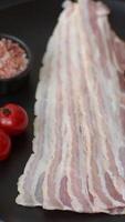Fresh raw bacon sliced with spices and herbs on a dark concrete background video