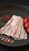 Fresh raw bacon sliced with spices and herbs on a dark concrete background video
