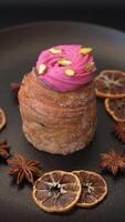 Sweet craffin or panettone garnished with raspberry and pistachio flavored cream on a dark concrete background video