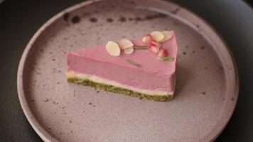 Piece of sweet cheesecake with pink cream cheese of raspberry or strawberry flavor on a dark textured background video
