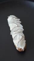 Sweet eclair with custard decorated with coconut slices on a dark concrete background video