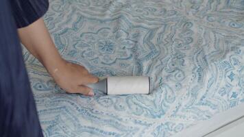 using an adhesive roller to remove lint and fluff from a bed . video