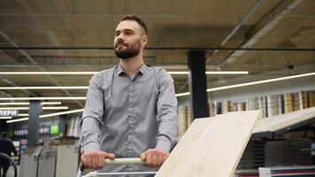 A man pushing trolley with new laminate in hardware store video