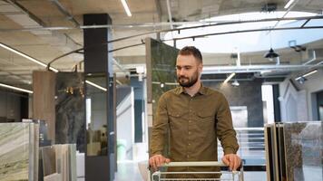 Handsome man walking with shopping cart at luxury shop and chooses tiles video