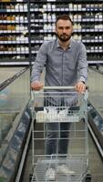 A man with shopping cart on escalator in a hardware store. Vertical video