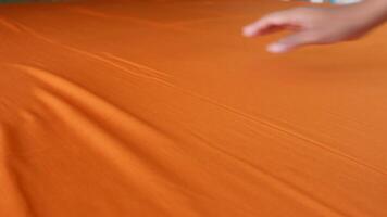Experience the thrill of hand gliding over a smooth, vibrant orange fabric surface video