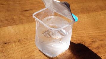 A Clear Water Container Inside a Plastic Bag Resting on a Beautiful Wooden Table video