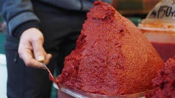 A vibrant red chili paste stored in a container, accompanied by a spoon for easy serving video