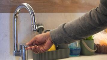 Hand Turning On Kitchen Faucet With Running Water video