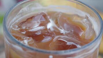 A closeup view of a refreshing Iced Coffee topped with creamy milk and ice cubes video