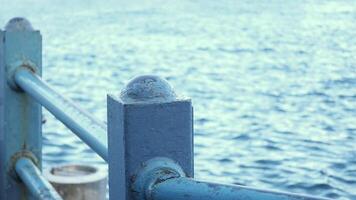 A detailed closeup view of a pier railing, beautifully framed with a serene ocean background video