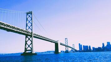 A bridge spanning over the water with a city in the background photo